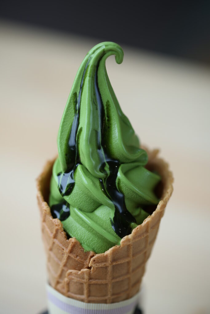 Green tea ice cream in a waffle cone topped with green tea syrup