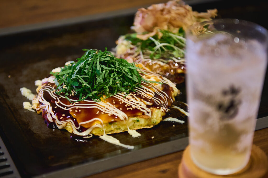 Okonomiyaki topped with sauce, mayonnaise, and shredded shiso leaves.