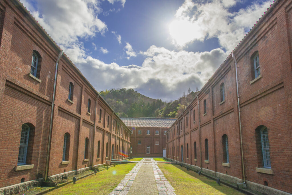 A pathway between brick buildings at Maizuru Red Brick Park on a sunny day