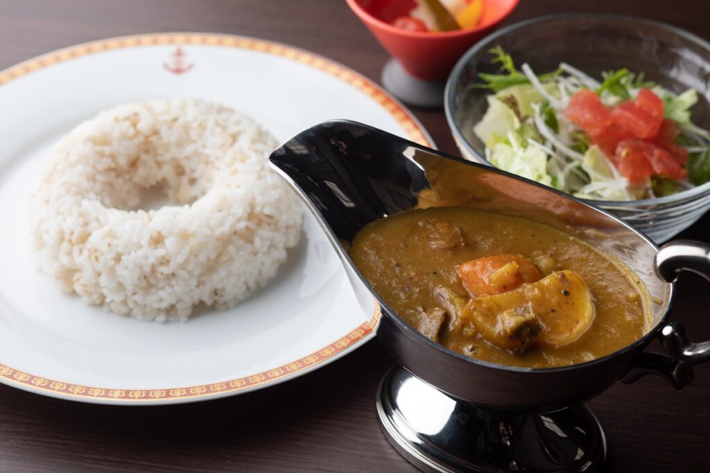 Shoeikan's curry in a gravy boat with a side of salad and plate of rice