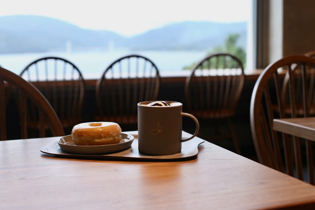 A donut on a plate and cup of coffee with a musical note etched into it at atick's cafe